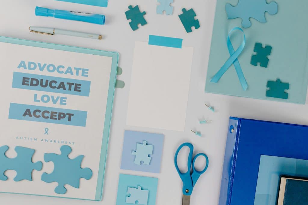 Autism awareness materials, including a blue ribbon and puzzle pieces, symbolizing NDIS support for individuals with autism.