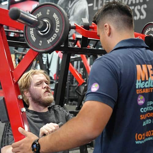 A participant using gym equipment with support from a Meta Healthcare professional