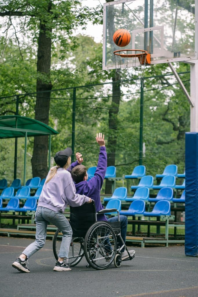 NDIS participant enjoying a basketball game with support worker, showcasing community access and inclusion.