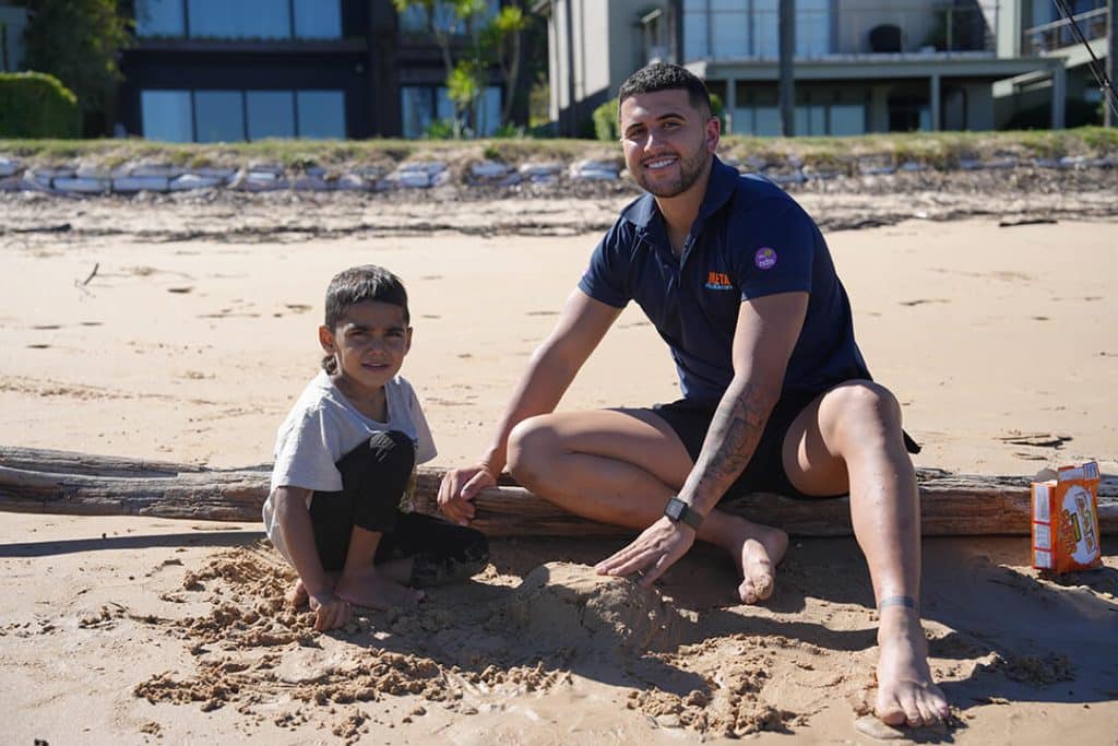 A man and a child playing in the sand at the beach on a sunny day.