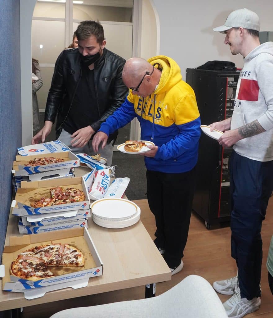 Colleagues enjoying pizza together during a team gathering.