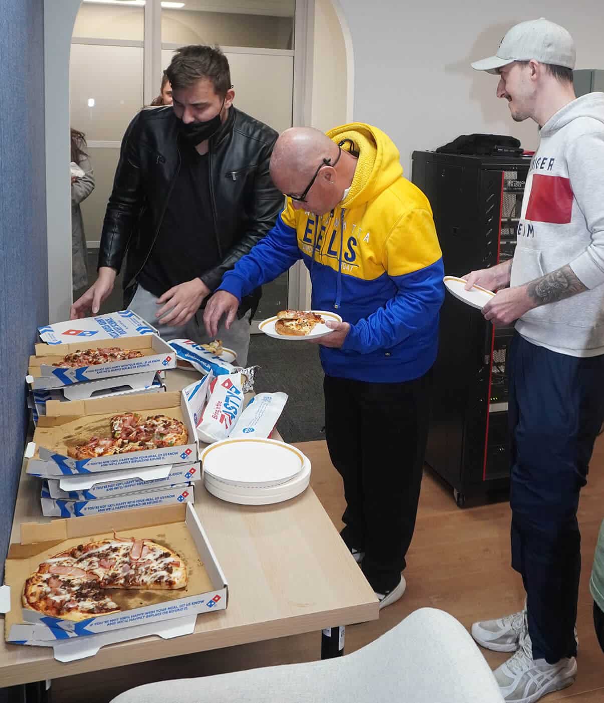 Colleagues enjoying pizza together during a team gathering.
