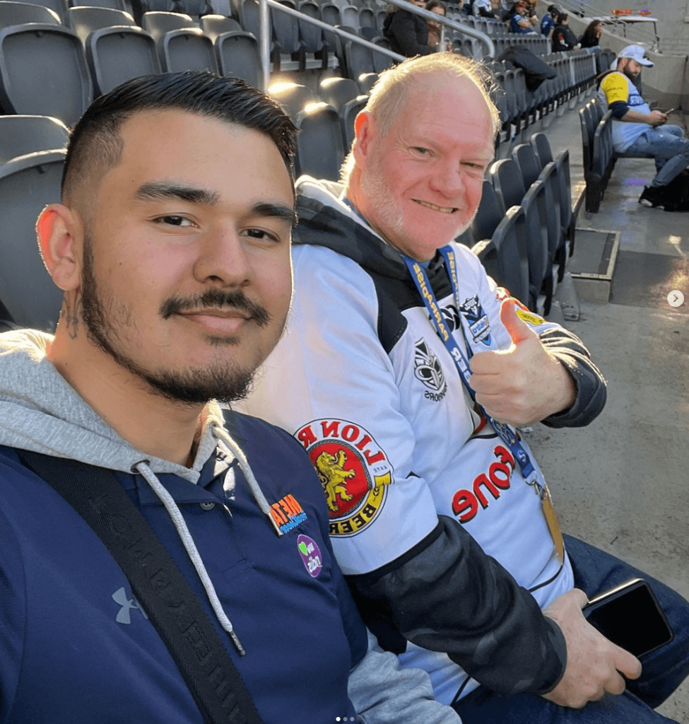 Two fans enjoying a game at the stadium, smiling and posing for a selfie.