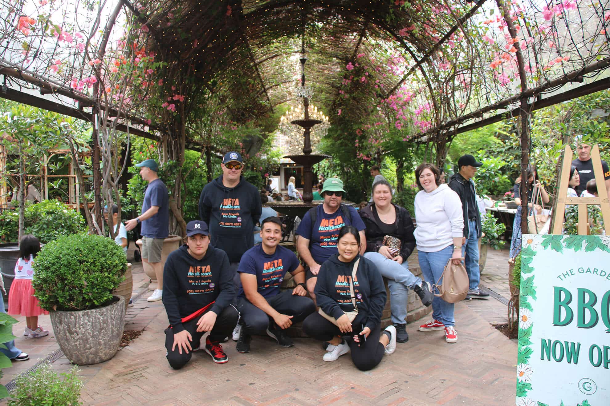 Friends posing in a blooming garden with colorful flowers and greenery.