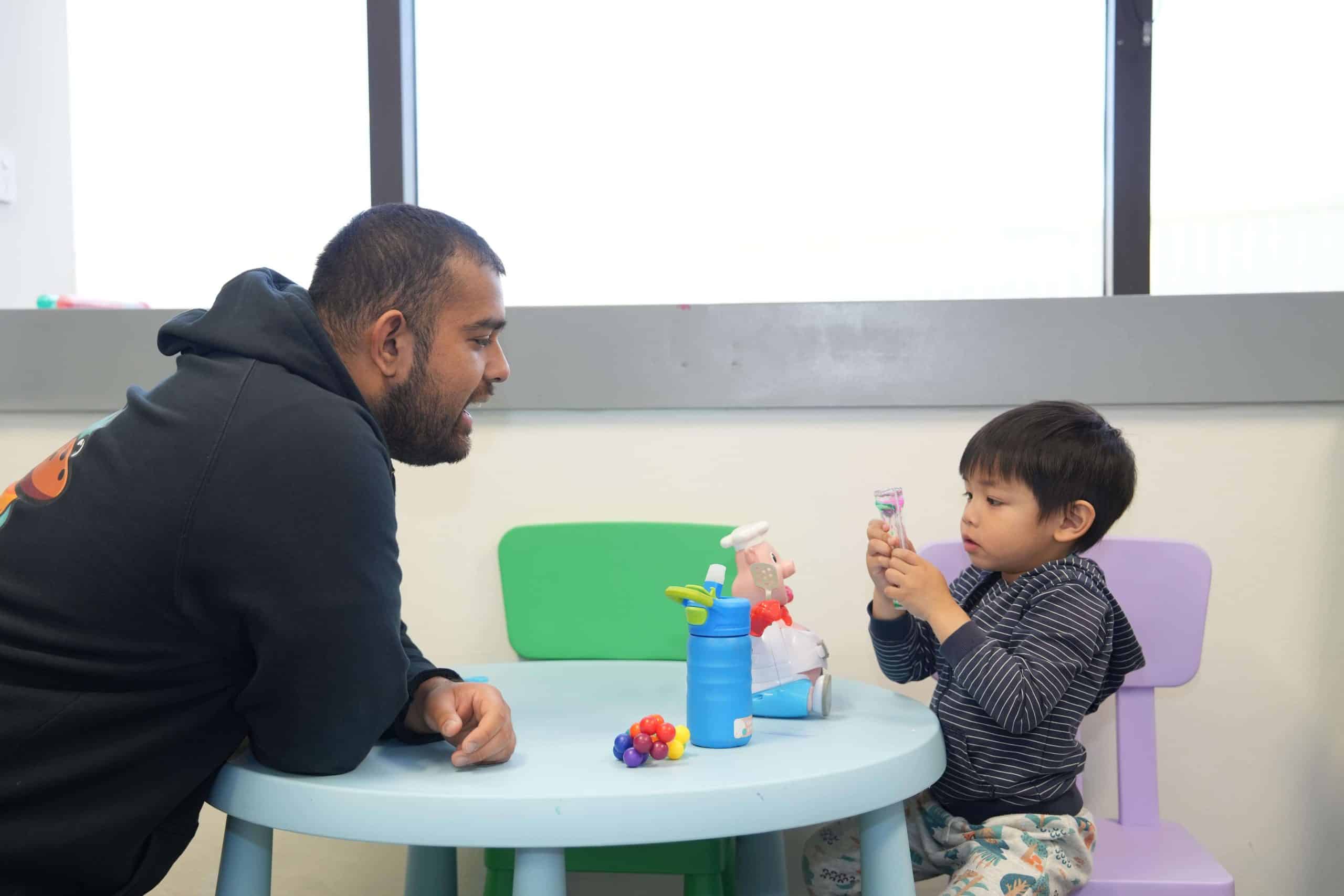 A young boy and an adult having a fun learning moment with toys.