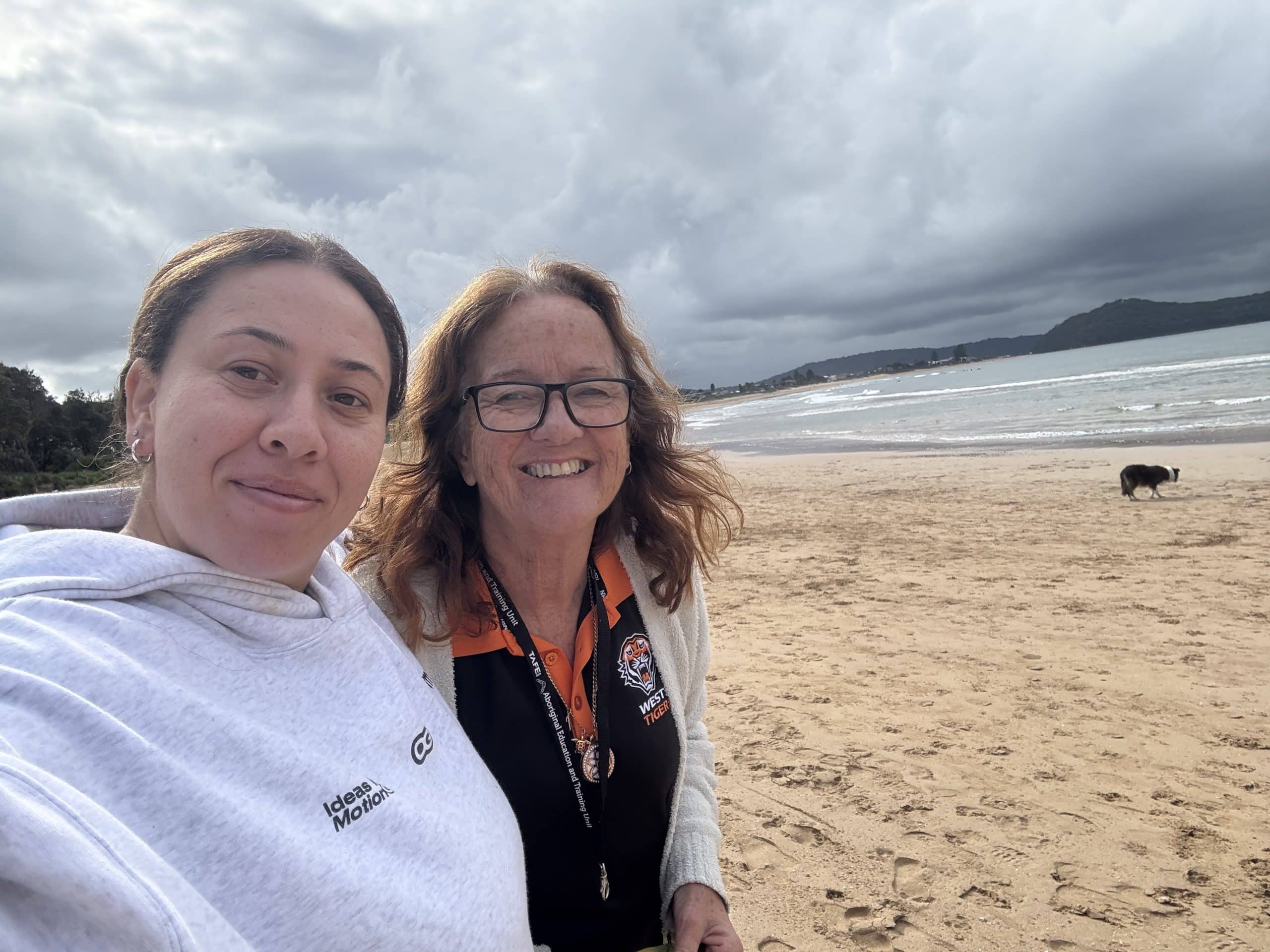 A participant and support worker enjoying a supported beach outing
